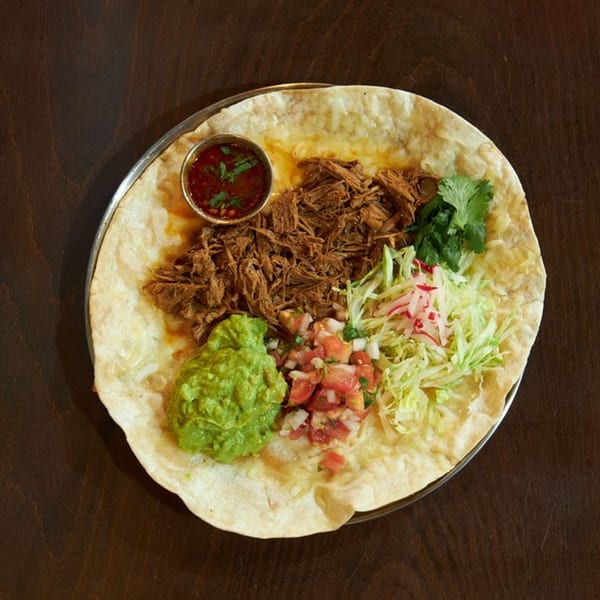 A large flour tortilla with shredded beef, guacamole, pico de gallo, shredded lettuce, and salsa.
